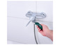 Une clé à molette verte est utilisée pour fixer une pomme de douche.