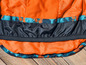 Une veste orange avec une doublure noire et un ourlet élastique.