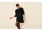 Femme portant une robe en maille noire et des collants noirs