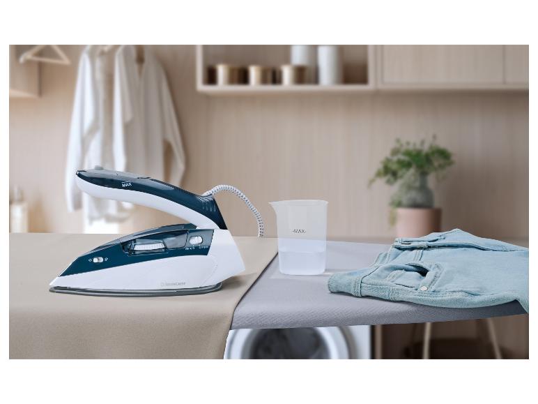 Fer à vapeur avec verre doseur et jean sur une planche à repasser dans une buanderie.