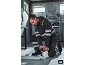 Homme en tenue de travail réfléchissante avec outil travaillant sur des structures métalliques.