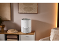 Purificateur d'air blanc sur un buffet en bois dans une pièce chaleureuse.