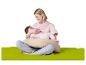 Mère souriante allaitant son bébé sur un coussin d'allaitement, assise sur un tapis vert.