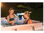 Deux femmes se détendent dans une piscine hors-sol avec une cascade lumineuse.