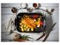 Cuiseur vapeur avec carottes, pommes de terre et poivrons, entouré d'épices et d'ustensiles de cuisine.