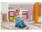Fille souriante avec une poupée Baby Annabell dans une chambre d'enfant avec un tapis rose.