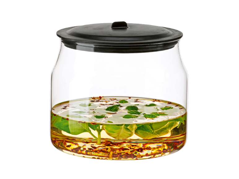 Bocal en verre pour conserves avec couvercle hermétique, rempli d'herbes et d'huile.