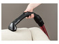 Une main utilisant un embout de brosse d'aspirateur pour nettoyer un canapé blanc.