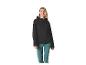 Femme en veste softshell noire et pantalon turquoise souriante.