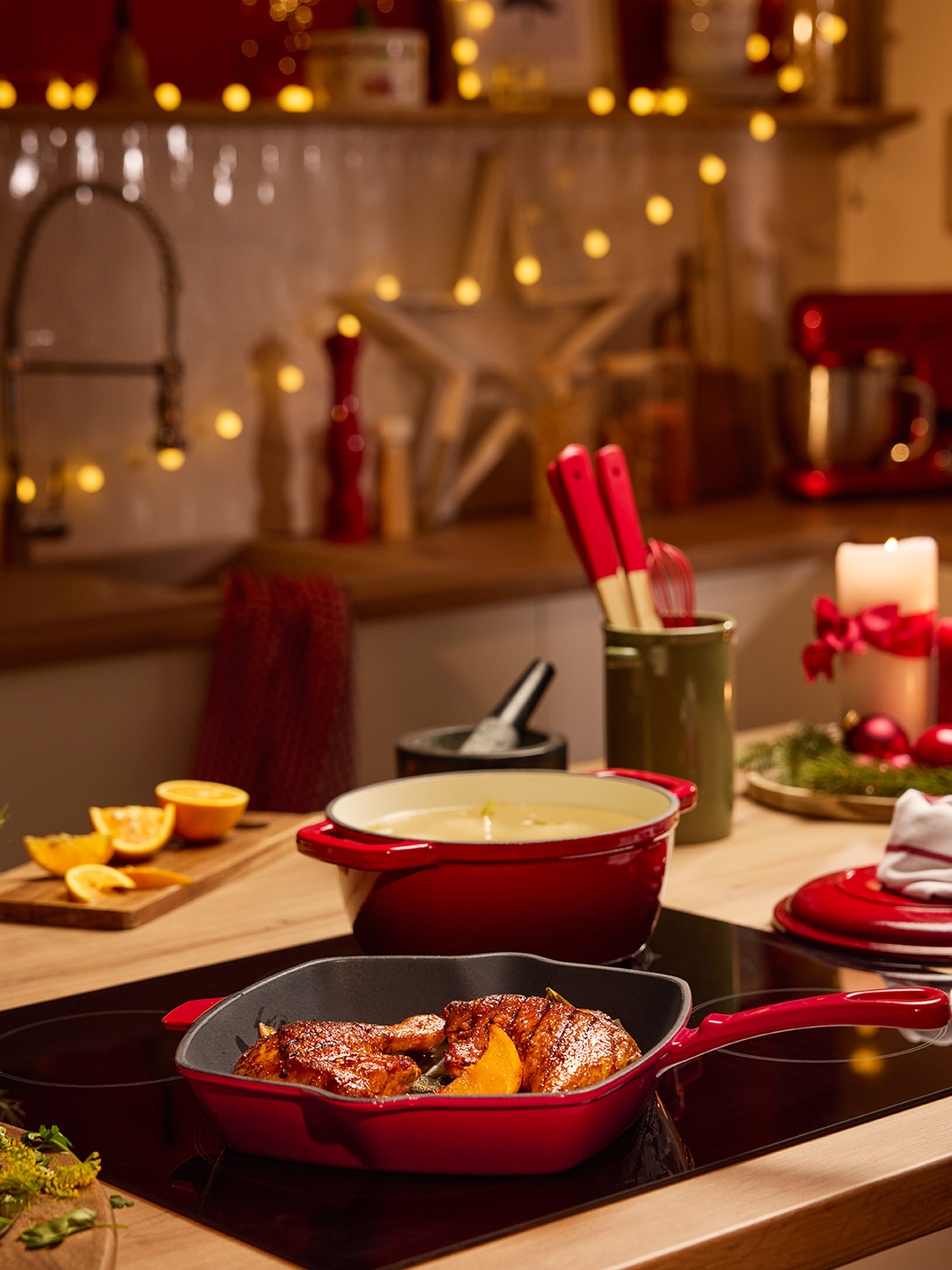 Casseroles et poêles rouges avec de la nourriture sur une plaque de cuisson dans une cuisine décorée pour Noël.