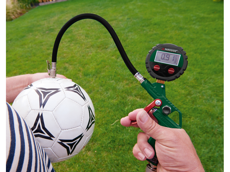 Manomètre numérique gonflant un ballon de football sur fond d'herbe.