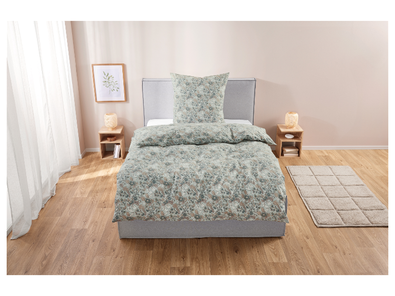 Parure de lit fleurie en vert et beige sur un lit gris.