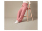 Une femme enceinte portant un pantalon large rose et des baskets blanches.