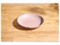 Bol rose vide sur une table en bois clair avec des ombres.