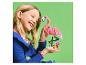 Une fille souriante tient un flamant rose en briques de construction et des fleurs.