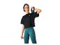 Femme en t-shirt noire courte et leggings bleus tenant un kettlebell.