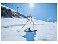 Une femme en veste et pantalon de ski blancs descend une piste.