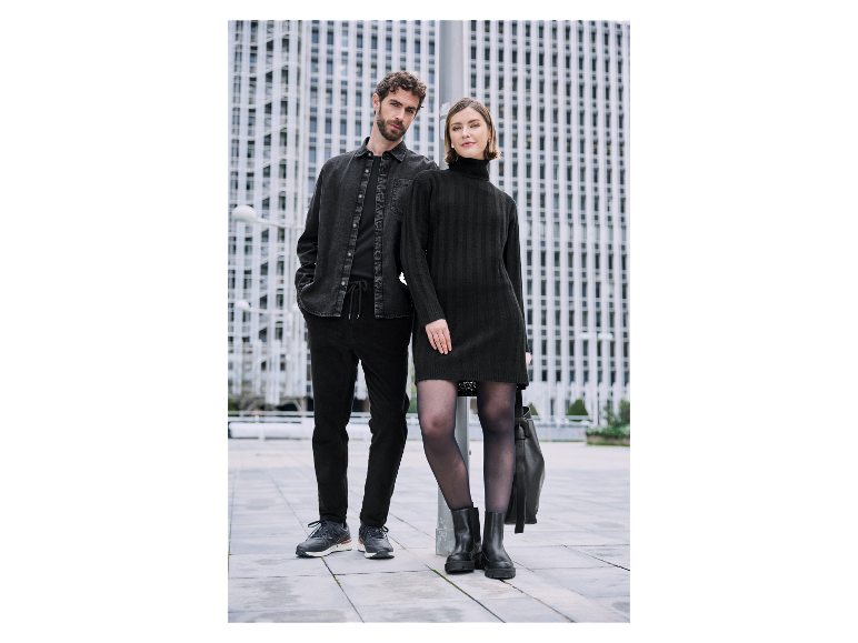 Couple en tenues noires élégantes posant devant un immeuble moderne.
