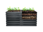 Plantes dans des bacs à jardin superposés : structure gris foncé et terreau visible.