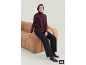 Femme en sans-manches en tricot violet, pantalon noir et bottines assise sur un canapé