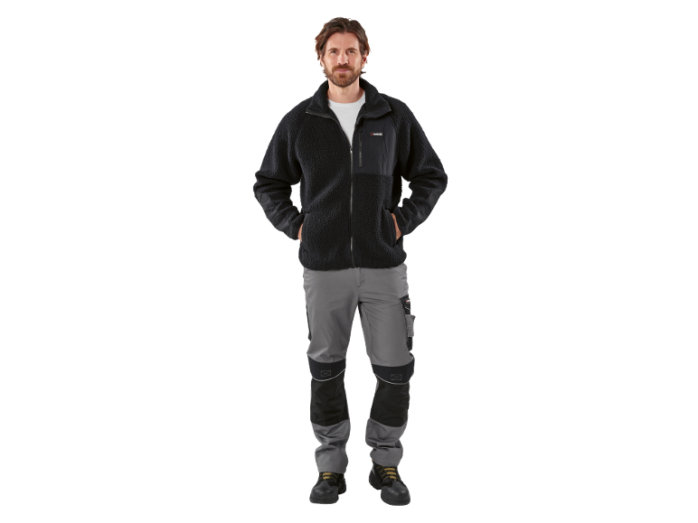 Homme portant une veste polaire noire et un pantalon de travail gris.