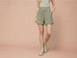 Femme portant un short vert à motif floral et des baskets beiges.