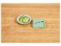 Concombre tranché dans une assiette blanche avec une mandoline verte sur une table en bois.