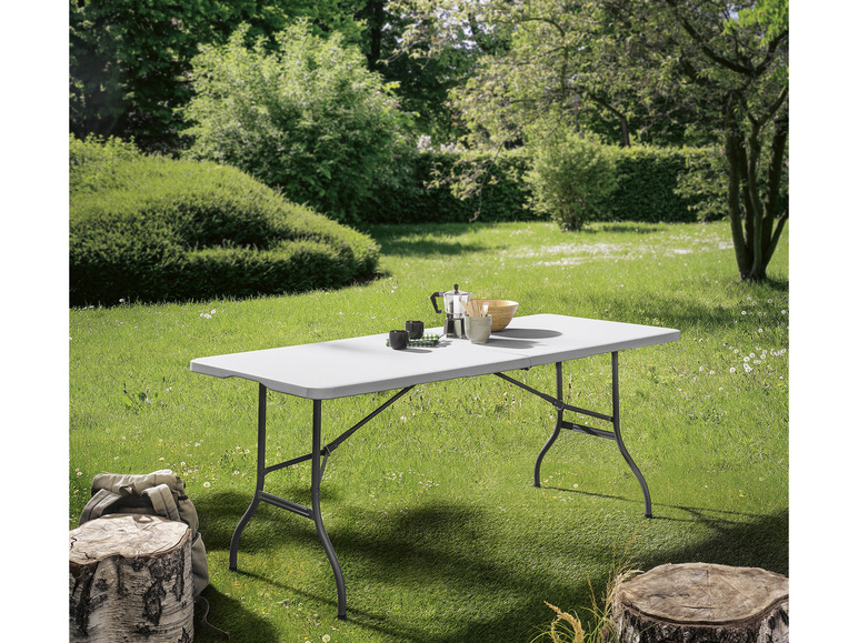 Une table pliante blanche dans un jardin.