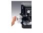 Machine à café noire avec buse vapeur, faisant mousser du lait dans un pichet en métal.