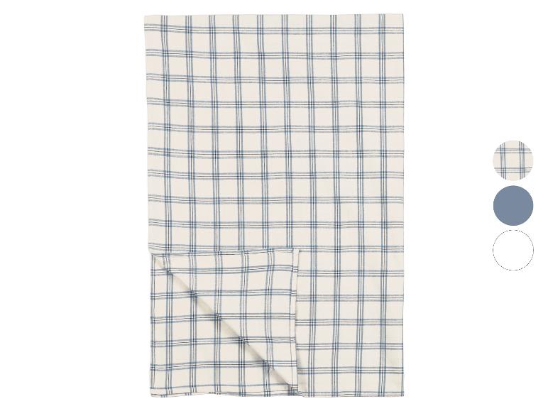 Nappe à carreaux crème avec des lignes bleues et noires, pliée sur fond blanc.