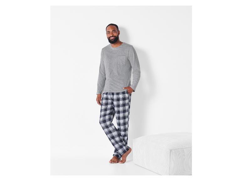 Homme en chemise à manches longues grise et pantalon de pyjama à carreaux.