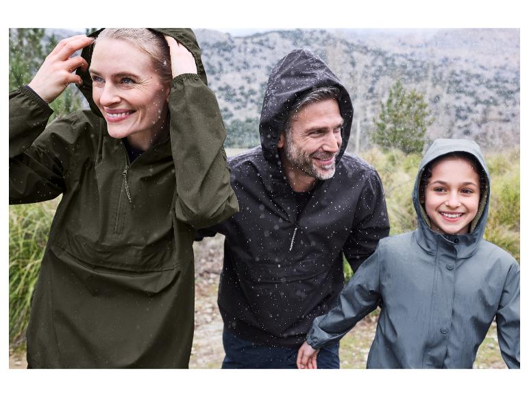 Une famille heureuse porte des vestes imperméables lors d'une promenade sous la pluie.