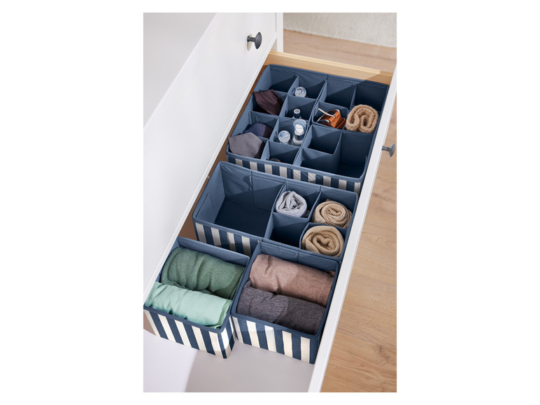 Boîtes de rangement dans un tiroir avec des vêtements et des accessoires.