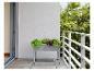 Un pot de fleurs gris avec des herbes sur un balcon.