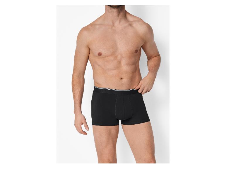 Homme torse nu, portant un boxer noir avec une bande blanche à la taille.