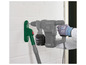 Un perforateur Parkside gris avec un aspirateur vert fixé à un mur