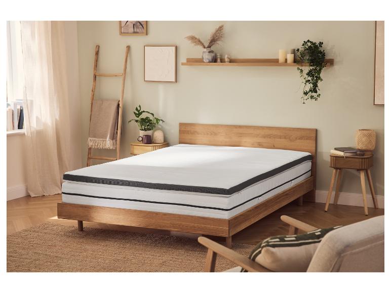 Chambre avec lit en bois, matelas et surmatelas, tables de chevet et décorations.