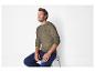 Un homme portant un pull vert en câble et un jean bleu.