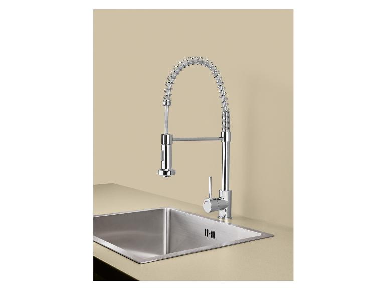 Robinet de cuisine chromé avec ressort et évier en acier inoxydable sur comptoir beige.