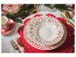 Une assiette blanche avec des détails rouges et dorés sur un set de table rouge.