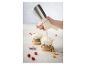 Une main utilise un siphon à crème pour ajouter de la crème fouettée à un verre de yaourt avec fruits et granola.