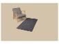 Fauteuil gris et tapis gris foncé sur fond beige.