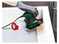 Une ponceuse verte avec aspirateur est utilisée pour poncer du bois.