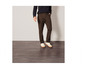 Un homme portant un pantalon chino brun foncé avec des baskets blanches.