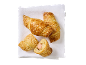 Croissants dorés aux saucisses, parsemés de sésame, sur une serviette blanche.