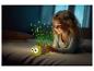 Petite fille joue avec une veilleuse tortue lumineuse dans son lit.