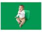 Bébé en body blanc à manches longues et pantalon beige, assis à côté d'un cube vert.