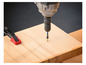 Un tournevis visse une vis dans une planche de bois.