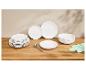 Assiettes et bols blancs empilés sur une table en bois avec des ombres de feuilles.