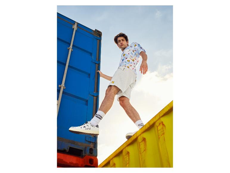 Modèle masculin portant un short, une chemise à motifs et des baskets Deluxe.